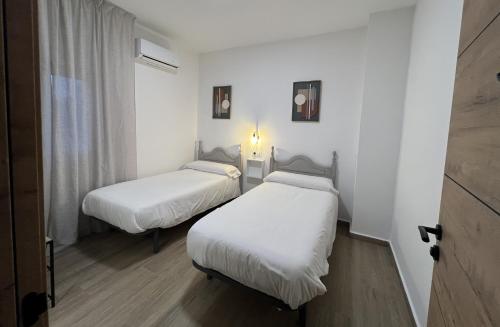 two beds in a room with white sheets at Casa rural Macondo in Trujillanos