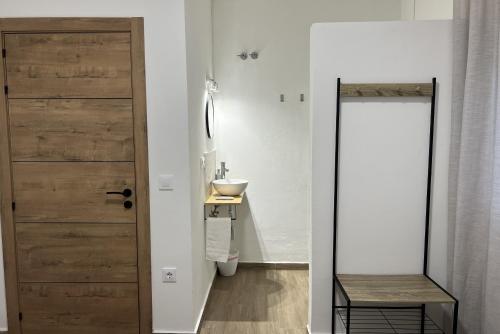 a bathroom with a wooden door and a sink at Casa rural Macondo in Trujillanos