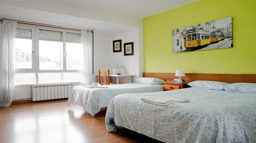 a bedroom with two beds and a yellow wall at Pension Santa Rita in Santiago de Compostela