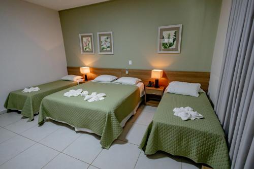 a hotel room with two beds with green blankets at Villa de Holanda Parque Hotel in Holambra