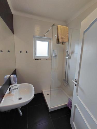 a white bathroom with a sink and a shower at Hostel Rosa in São Pedro de Moel