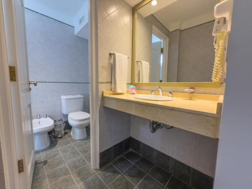 a bathroom with a sink and a toilet and a mirror at GRAN PALAZZO Hotel in Villa Gesell