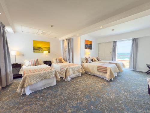 a hotel room with three beds and a large window at GRAN PALAZZO Hotel in Villa Gesell