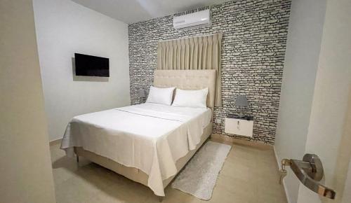 a bedroom with a white bed and a brick wall at MB Apartment - A in San Felipe de Puerto Plata