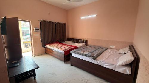 a bedroom with two beds and a table and a window at Amrit Guest House in Vrindāvan