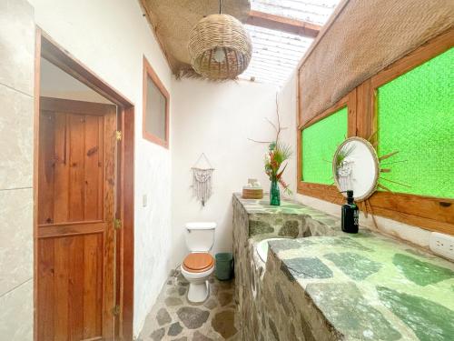a bathroom with a toilet and a green window at Granja Tzikin in Tzununá