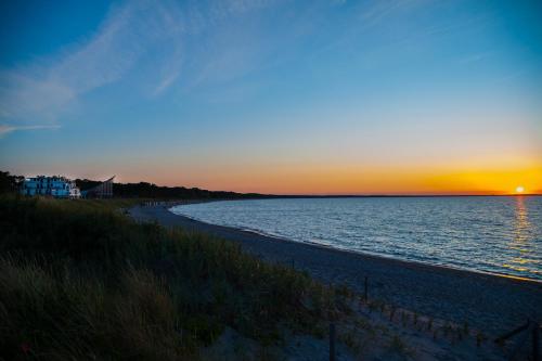 a sunset over a beach with the sun setting at Aparthotel Ostseeperle Glowe - schön gestrandet in Glowe