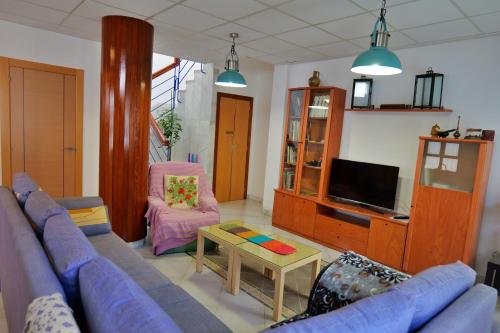 a living room with a blue couch and a tv at Casa Rural La Caja in Cogollos De La Vega