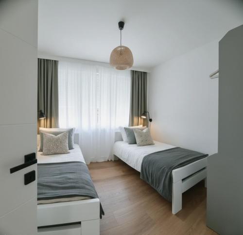 two beds in a room with white walls and wood floors at Apartment Rea in Čapljina