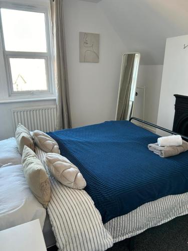 a bedroom with a bed with blue sheets and a window at Brand New Convenient Apartments Folkestone in Folkestone