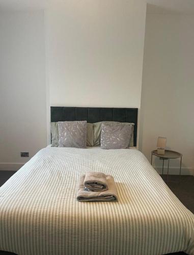 a bed with a blanket and a towel on it at Brand New Convenient Apartments Folkestone in Folkestone