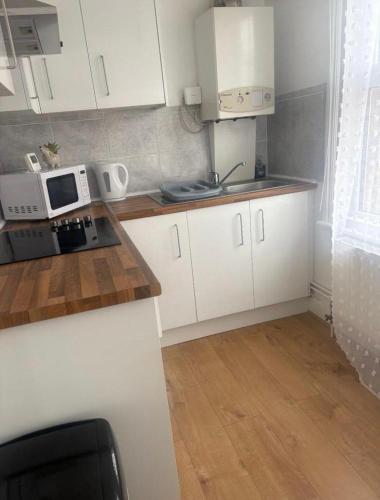 a small kitchen with white cabinets and a microwave at Brand New Convenient Apartments Folkestone in Folkestone