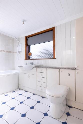 a white bathroom with a toilet and a sink at Hill Street Haven in Inverness