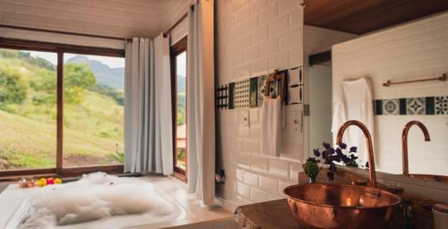 a bathroom with a tub and a large window at Pousada Canto do Papagaio in Aiuruoca