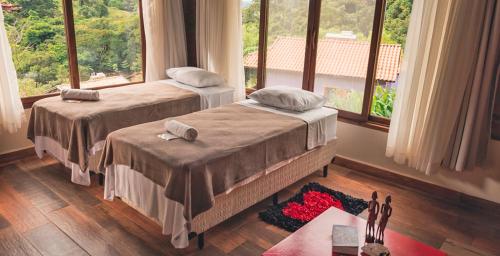 a bedroom with two beds and a large window at Pousada Canto do Papagaio in Aiuruoca
