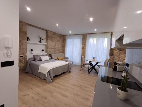 a bedroom with a bed and a table and a kitchen at Apartamentos Porta do Espolón in Noya