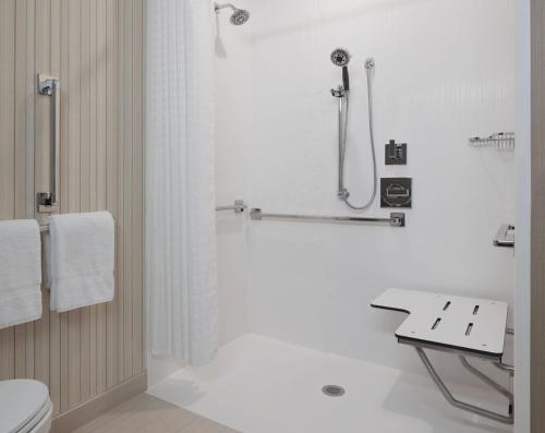 a white bathroom with a shower and a toilet at Courtyard Denver Aurora in Aurora
