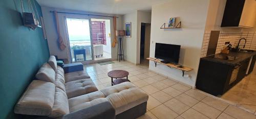 a living room with a couch and a television at KAZ Les pêchers in Saint-Denis