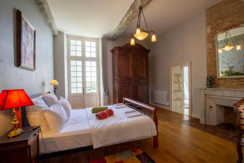 a bedroom with a bed with white sheets and a fireplace at La Gironie in Pomport