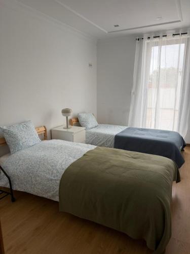 a bedroom with two beds and a window at Elegant Getaway - Spacious 3 Bedroom Apartment -Lisbon Baixa da Banheira in Lavradio