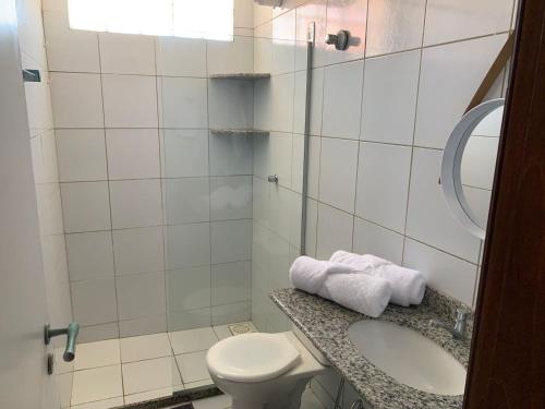 a bathroom with a toilet and a sink with towels at Oca Teko Porã in Genipabu