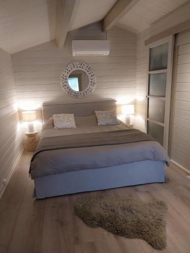 a bedroom with a bed with a mirror and a rug at Chalet cosy avec terrasse & hamac, calme, proche plage, parking, NC Properties in Grimaud