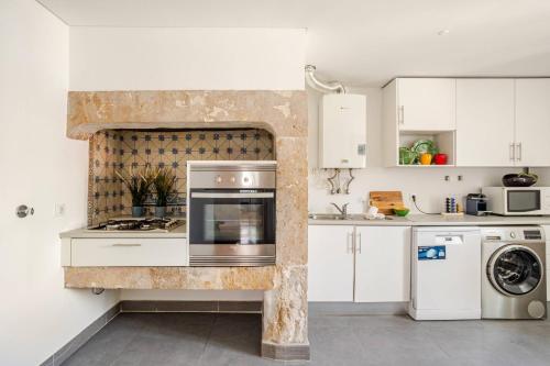 a kitchen with white cabinets and a stove top oven at Boutique duplex in Chiado with epic Rossio view in Lisbon