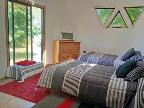 a bedroom with two beds and a dresser and a window at Domo familiar in Chillán