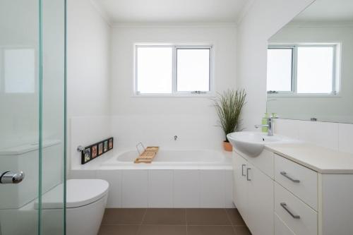 a bathroom with a tub and a toilet and a sink at Evergreen by the Bay in Sandringham