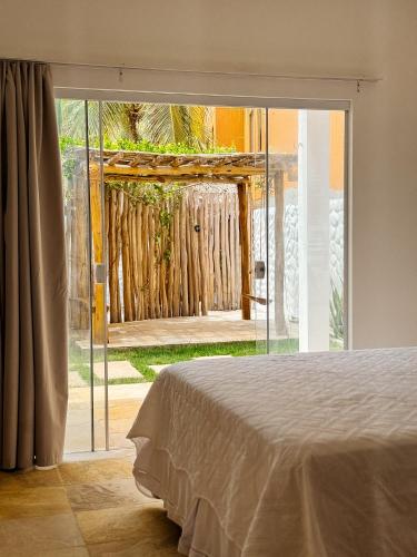 a bedroom with a sliding glass door to a yard at Pousada Vila Didi - Flats com Cozinha Completa in Barra Grande