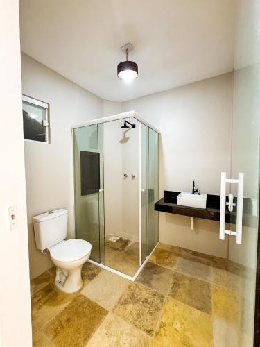 a bathroom with a toilet and a glass shower at Pousada Vila Didi - Flats com Cozinha Completa in Barra Grande