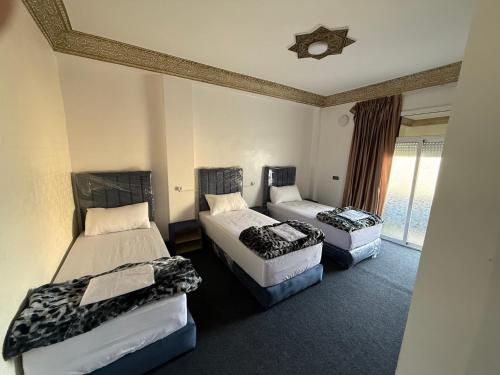 a hotel room with two beds and a window at Fes Apartment 2 in Fez