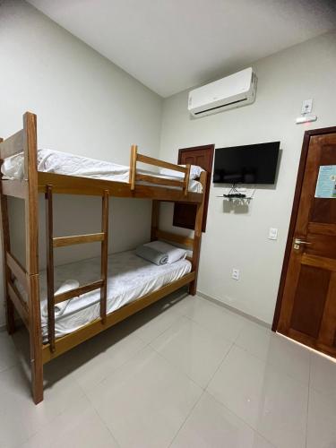 a room with bunk beds and a flat screen tv at Chalé Rota Das Dunas in Barreirinhas