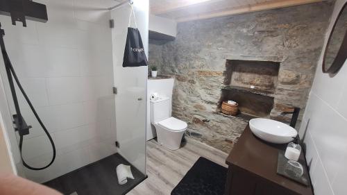 a bathroom with a toilet and a stone fireplace at Casas do Caminho in Lousã