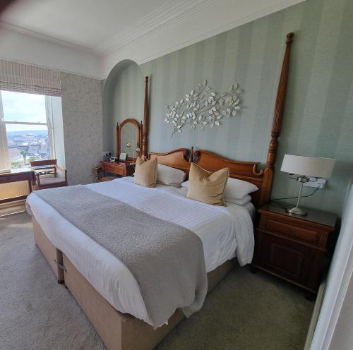 a bedroom with a large bed with a chandelier at Hotel Penzance Harbour View in Penzance
