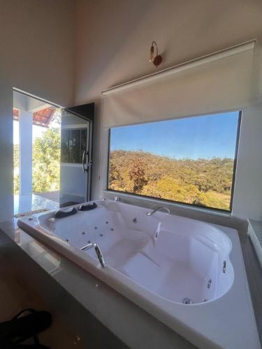 a large bath tub in a bathroom with a large window at Chalé Bella Vista 03 in Água Boa