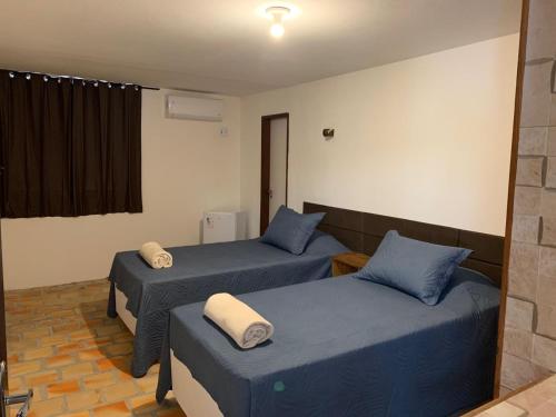 two beds in a room with blue sheets at Oca Teko Porã in Genipabu