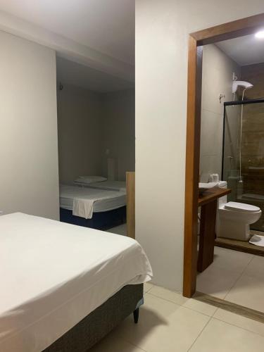 a bedroom with a bed and a bathroom with a sink at Hotel Zona Sul in São Gabriel