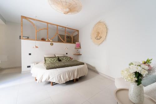 a white bedroom with a bed and a vase of flowers at L'Escale - Une parenthèse en duo in Châteauneuf-du-Pape
