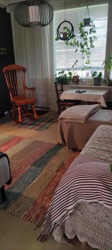 a room with two beds and a chair and a table at Kerrostalomajoitus in Riihimäki