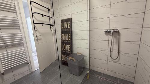 a bathroom with a shower with a sign on the wall at Apartman Vrućica view in Teslić
