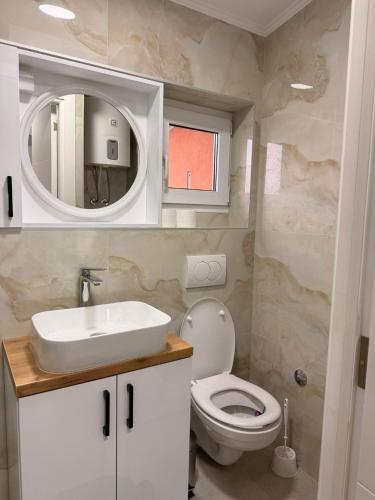 a bathroom with a toilet and a sink and a mirror at Apartman Krznarić Centar in Županja
