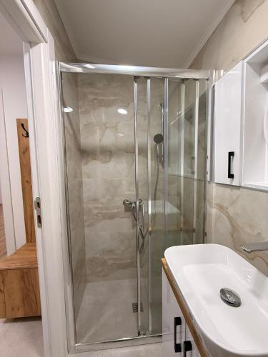 a shower with a glass door next to a sink at Apartman Krznarić Centar in Županja