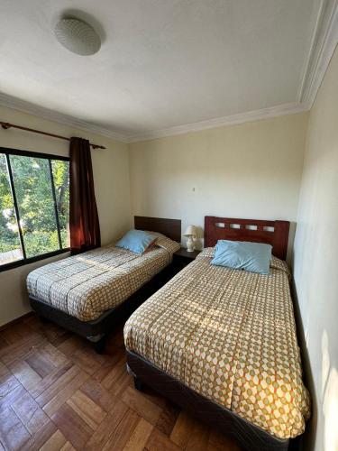ein Schlafzimmer mit zwei Betten und einem Fenster in der Unterkunft El Centrito in Talca
