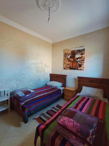 a bedroom with two beds and a painting on the wall at AZULI ⵣ Hostel Mirleft in Mirleft