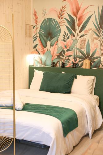 Un dormitorio con una cama grande con papel pintado tropical. en Le Studio Vert, en La Flèche