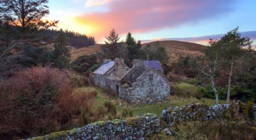 an old stone house in the middle of a field at Teach Hudi Beag, Bar & Accommodation Bunbeg in Bunbeg