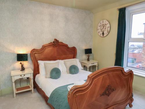 a bedroom with a wooden bed with two tables and a window at Rutland Grange in Filey