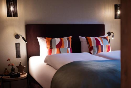 a bedroom with a large bed with colorful pillows at Landgasthaus & Hotel zur Krone in Dahn