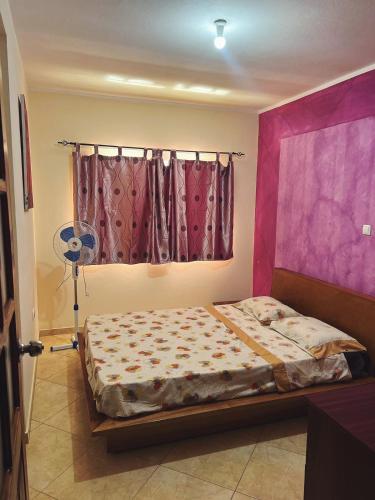 a bedroom with a bed with pink walls and a window at Tropical Breeze Holidays in Santa Maria